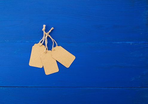 set of empty brown empty tags for clothes and other purposes on a blue wooden background. Paper craft