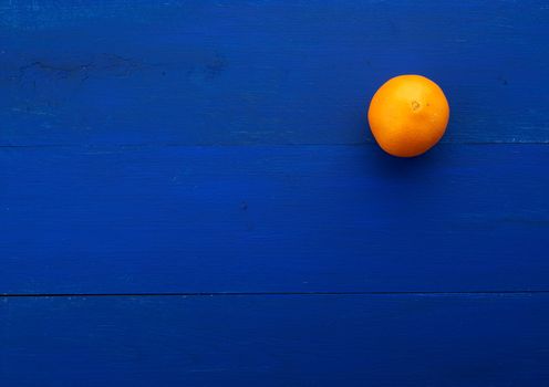 whole orange round orange on a dark blue background from boards painted in blue trend color, place for inscription