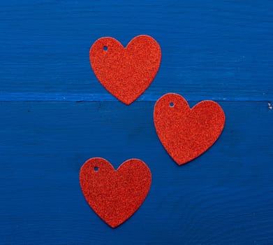 paper red shiny decorative hearts on dark blue wooden background, abstract festive backdrop for valentines day february 14