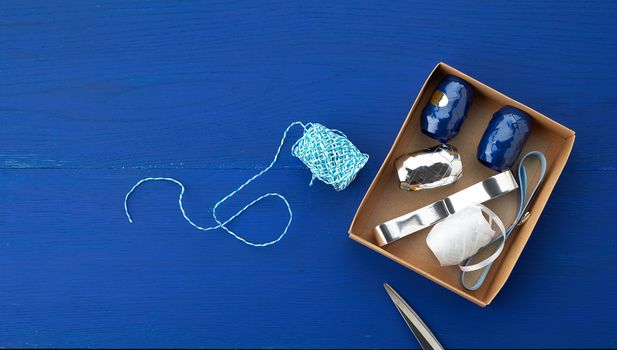 brown cardboard box with a set of decor ribbons for wrapping gifts on a dark blue background, top view