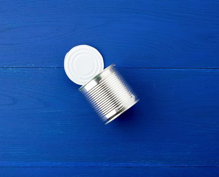 open large metal tin can on a blue wooden background from parallel boards, top view