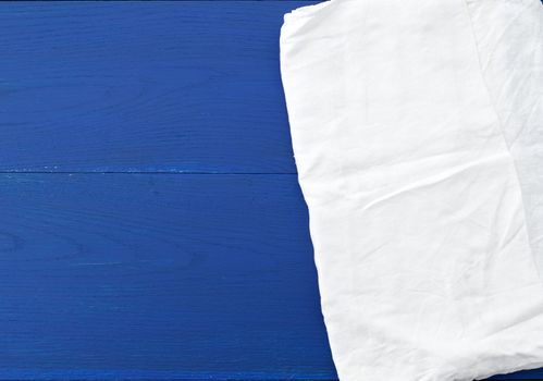 white kitchen textile towel folded on a blue wooden table from old boards, top view, empty space. Decoration element.