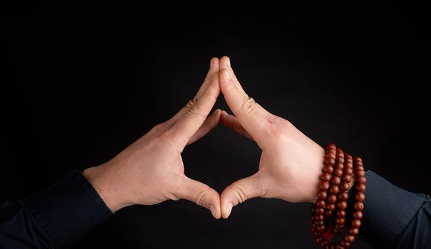 two male hands connected on a black background, demonstration of mudra soaring lotus