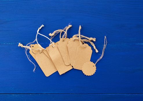 set of empty brown empty tags for clothes and other purposes on a blue wooden background. Sale, price tag