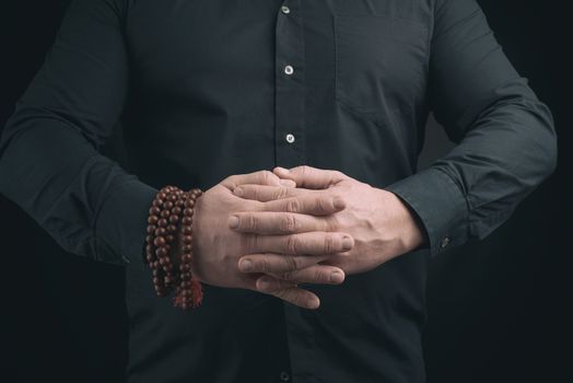 man in a black shirt crossed his arms in front of the torso, performing mudra, meditation