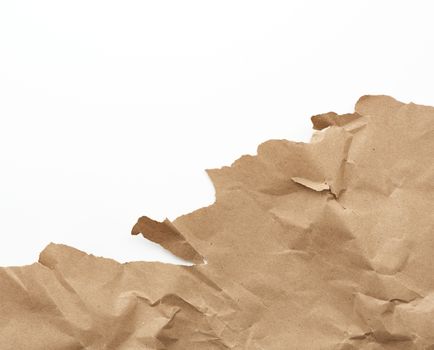 fragment of a crumpled blank sheet of brown wrapping kraft paper with torn edges, vintage texture for the designer, full frame. Torn paper sheet