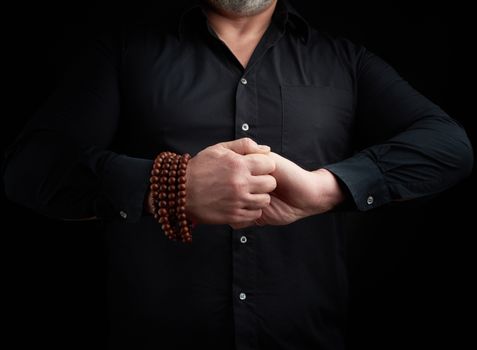 man in a black shirt crossed his arms in front of the torso, performing mudra, meditation