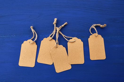 set of empty brown empty tags for clothes and other purposes on a blue wooden background. Paper craft