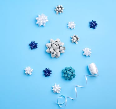 related white, blue and gray bows for gifts on a blue background, decor for decorating gifts, top view
