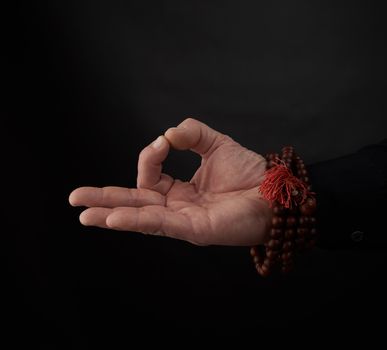 male hand shows the mudra of Knowledge on a black background, the concept of relaxation and meditation