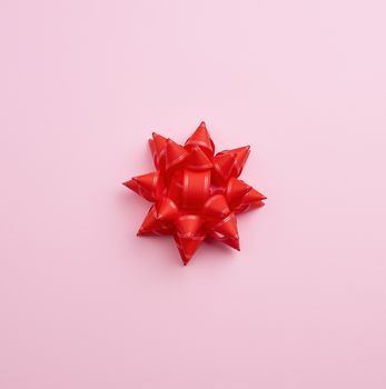 big red beautiful bow on a pink background, a festive element for the designer, copy space