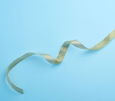 Shiny golden satin ribbon on a blue background. Beautiful banner for celebration design. Anniversary, birthday