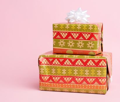 stack of colored paper wrapped gift boxes. great design for any purposes, pink background 