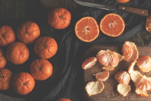 ripe round tangerines and cut in half on an old vintage cutting board. Healthy vegetarian food. Citrus fruit.