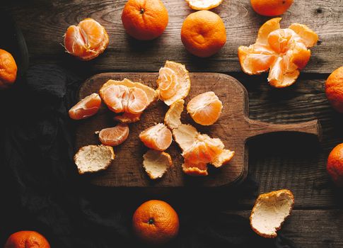 ripe round tangerines and cut in half on an old vintage cutting board. Healthy vegetarian food. Citrus fruit, top view