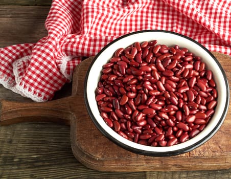 raw oval red beans in a plate on a wooden table. Organic meal. Vegetarian healthy natural food.