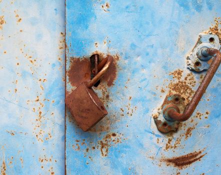 old rusty lock hanging on a blue metal door, full frame