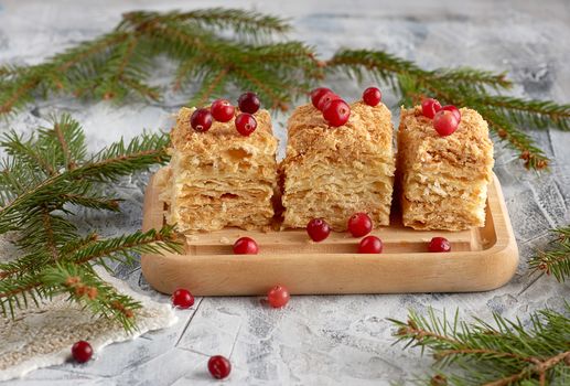 pieces of baked layer of cake Napoleon with butter cream on a wooden board, close up