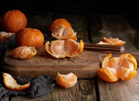 ripe round tangerines and cut in half on an old vintage cutting board. Healthy vegetarian food. Citrus fruit
