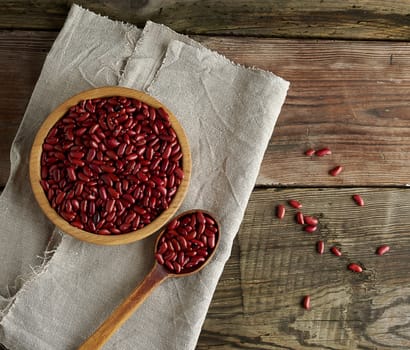 raw oval red beans in a plate on a wooden table. Organic meal. Vegetarian healthy natural food.