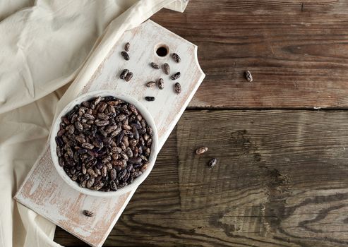raw oval red marble beans in a plate on a wooden table. Agriculture harvest. Vegetarian healthy natural food.