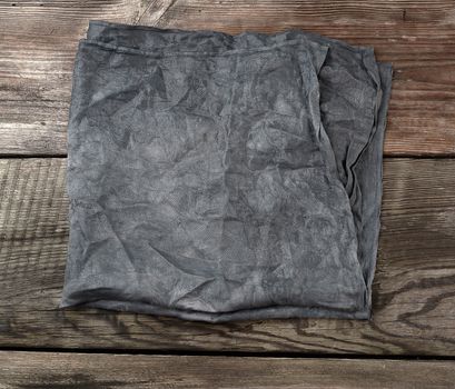 black textile kitchen towel on a wooden background from old gray boards, place for an inscription, top view