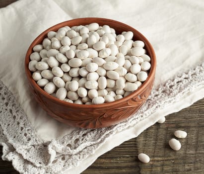 raw round white beans in a plate on a wooden table. Organic meal. Vegetarian healthy natural food.