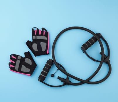 sports gloves and rubber hand exercise machine on a blue background, top view