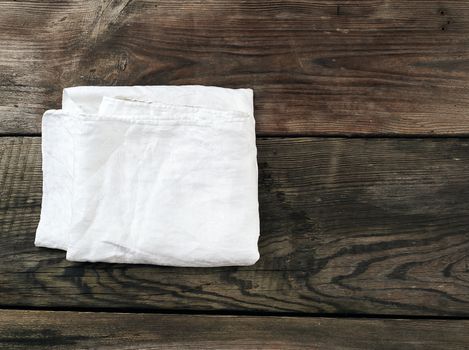 white kitchen textile towel folded on a gray wooden table from old boards, top view, empty space. Rustic texture. Retro background