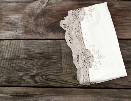 white kitchen textile lace towel folded on a gray wooden table from old boards, top view, empty space