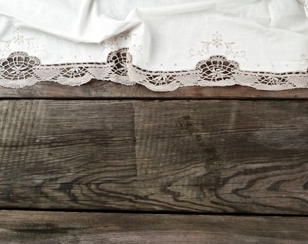 white kitchen textile lace towel folded on a gray wooden table from old boards, top view, empty space