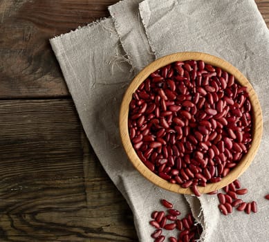 raw oval red beans in a plate on a wooden table. Organic meal. Vegetarian healthy natural food.