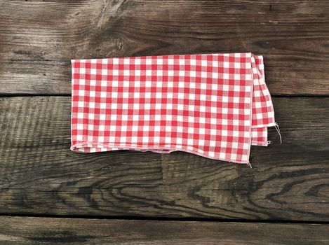 red-white textile kitchen towel on a wooden background from old gray boards, place for an inscription