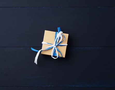 brown cardboard gift square box on a blue wooden background, top view. Festive concept, copy space