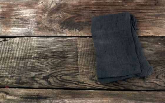black kitchen textile towel folded on a gray wooden table from old boards, top view, empty space. Rustic texture. Retro background