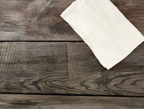white kitchen textile towel folded on a gray wooden table from old boards, top view, empty space. Rustic texture. Retro background