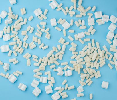 scattered white foam for packaging parcels on a blue background, full frame