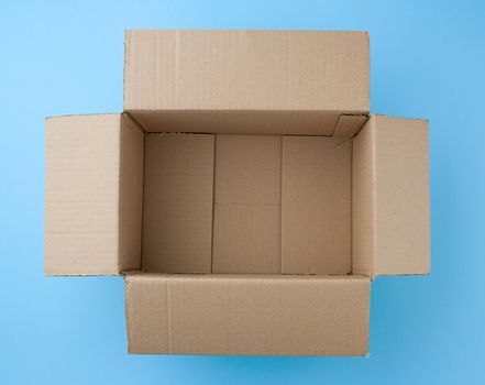 open empty square brown cardboard box for transportation and packaging of goods on blue background, top view.