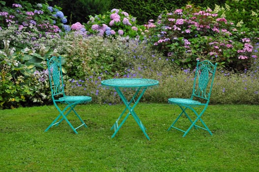 Green decorative garden table and chairs on the lawn