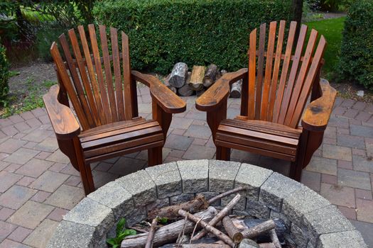 Two wooden adirondack chairs and campfire