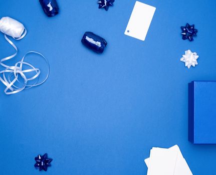 cardboard gift square boxes, bows, ribbons for packaging on a dark blue background, empty space in the middle, trend colors