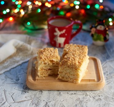 stack of slices of Napoleon cake made of puff pastry and butter cream, behind burning garlands