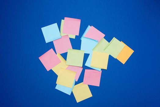 multicolored blank paper stickers of different colors on a dark blue background, copy space