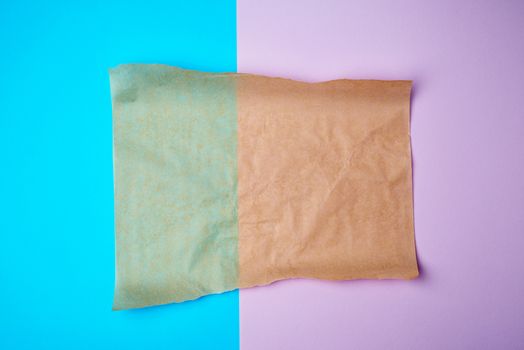 empty brown sheet of parchment paper with curled edges on a colored background, copy space