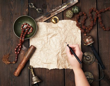 tibetan religious objects for meditation and alternative medicine, empty brown sheet of paper on a brown wooden background, top view, copy space