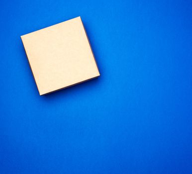 closed blue cardboard gift square box on a dark blue background, top view, trend colors