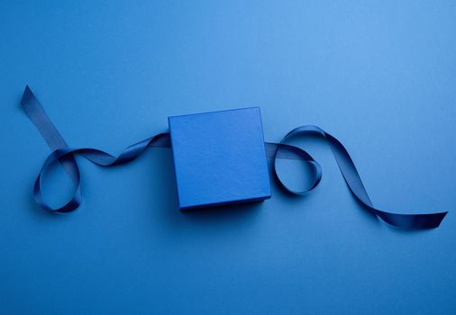 closed cardboard gift square box, ribbons for packaging on a dark blue background, top view, trend colors