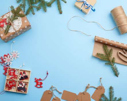roll of brown wrapping paper, decor, spruce branches, Christmas toys and boxes with gifts on a blue background, top view. Christmas holiday concept