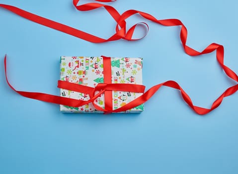 gift wrapped in multi-colored paper on a blue background, festive backdrop, top view