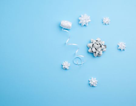 knitted white bows and white ribbon on a blue background, decor for decorating gifts, top view